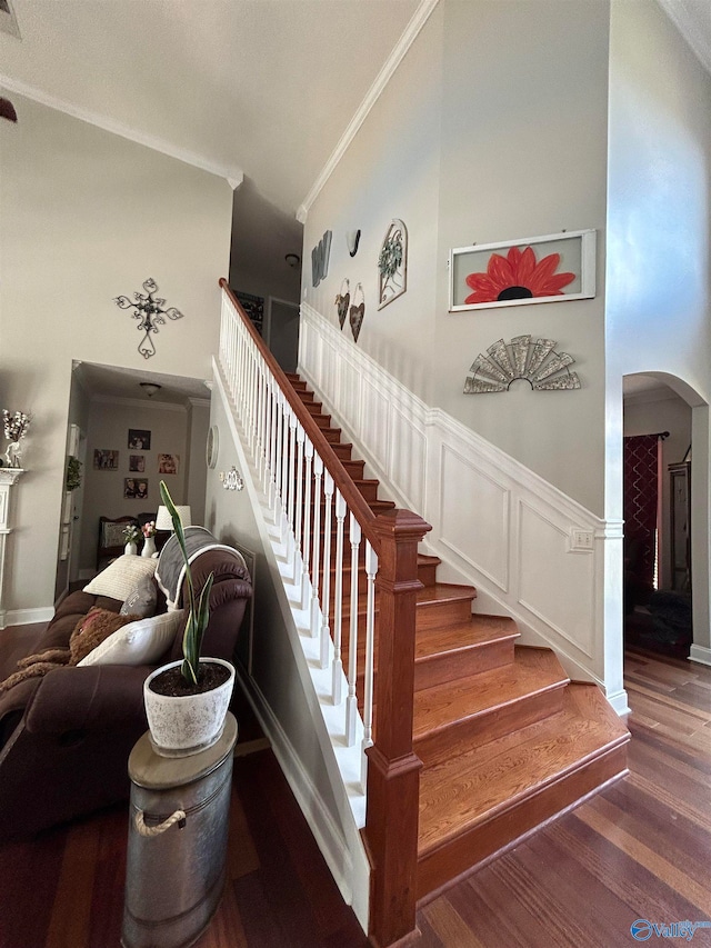 stairway with ornamental molding and hardwood / wood-style floors