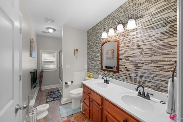 bathroom with decorative backsplash, vanity, walk in shower, wood-type flooring, and toilet