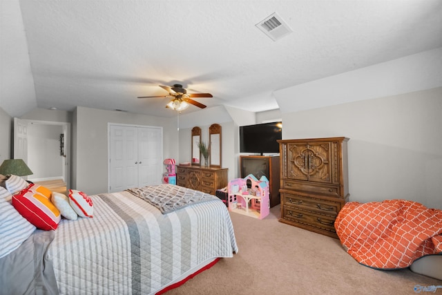 bedroom with ceiling fan, light colored carpet, a textured ceiling, and a closet