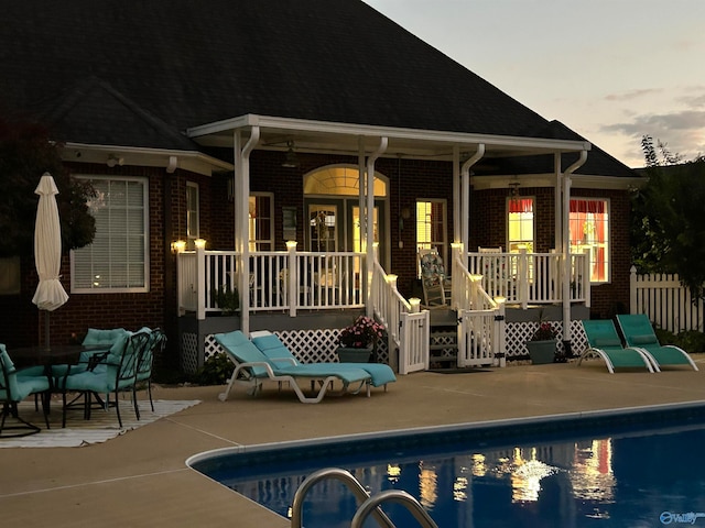 back house at dusk with ceiling fan and a patio area