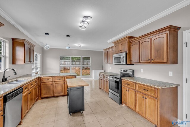 kitchen featuring stainless steel appliances, crown molding, a center island, decorative light fixtures, and sink