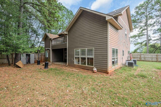 rear view of property featuring a lawn and central air condition unit