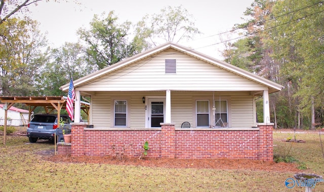 bungalow with a front yard, a porch, and a carport