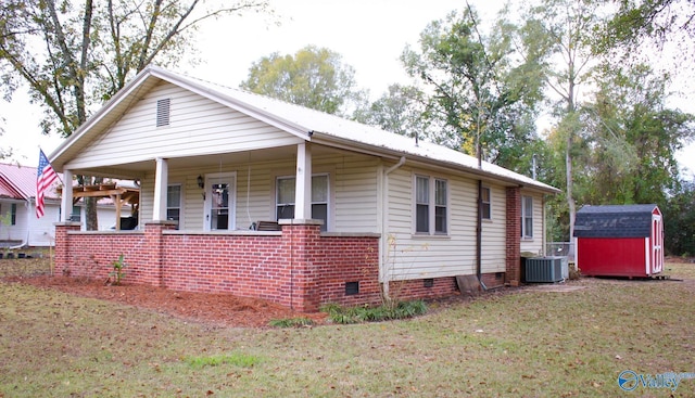 view of front of house with covered porch, a storage shed, central air condition unit, and a front lawn