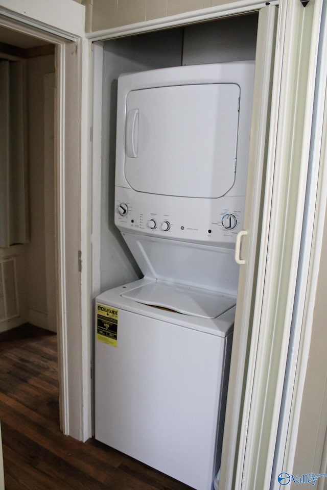 laundry area featuring stacked washing maching and dryer and dark hardwood / wood-style floors