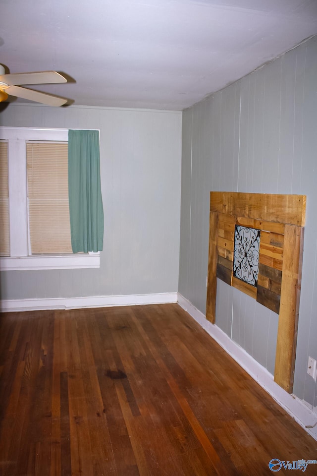 unfurnished living room with ceiling fan, dark hardwood / wood-style flooring, and wooden walls