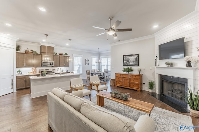 living area with recessed lighting, a fireplace, a ceiling fan, dark wood finished floors, and crown molding