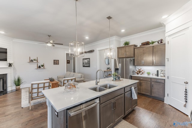 kitchen with open floor plan, a kitchen island with sink, stainless steel appliances, light countertops, and a sink