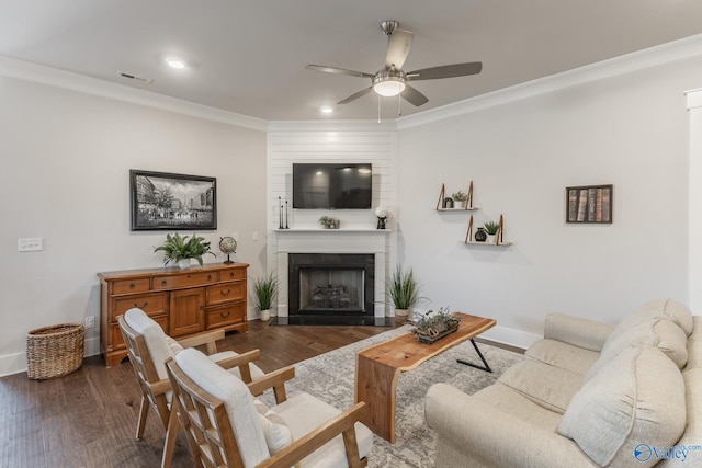 living room with dark wood-type flooring, visible vents, crown molding, and a fireplace