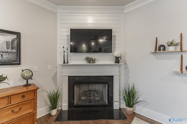 living area featuring ornamental molding, a fireplace, baseboards, and wood finished floors