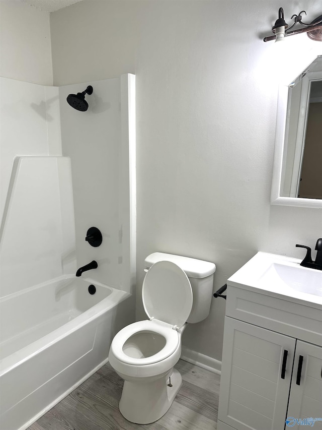 bathroom with baseboards, toilet, vanity, wood finished floors, and shower / bathtub combination