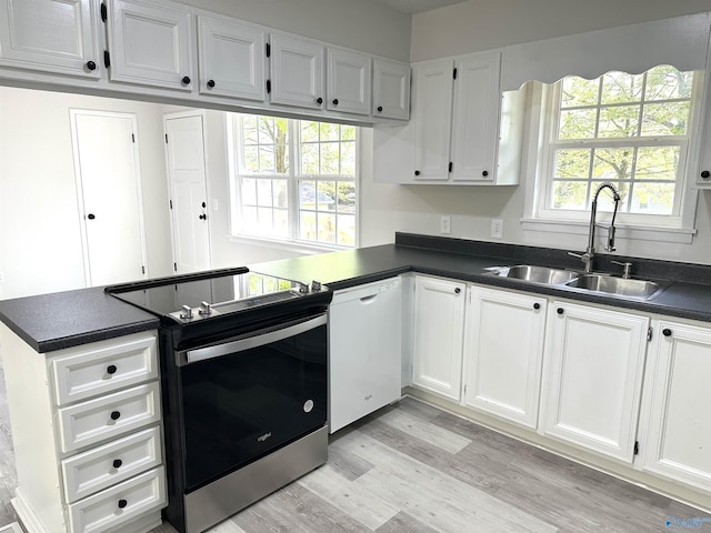 kitchen with white cabinetry, dark countertops, a sink, white dishwasher, and electric stove