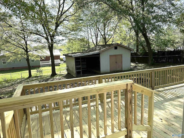 deck with an outbuilding, a shed, and fence