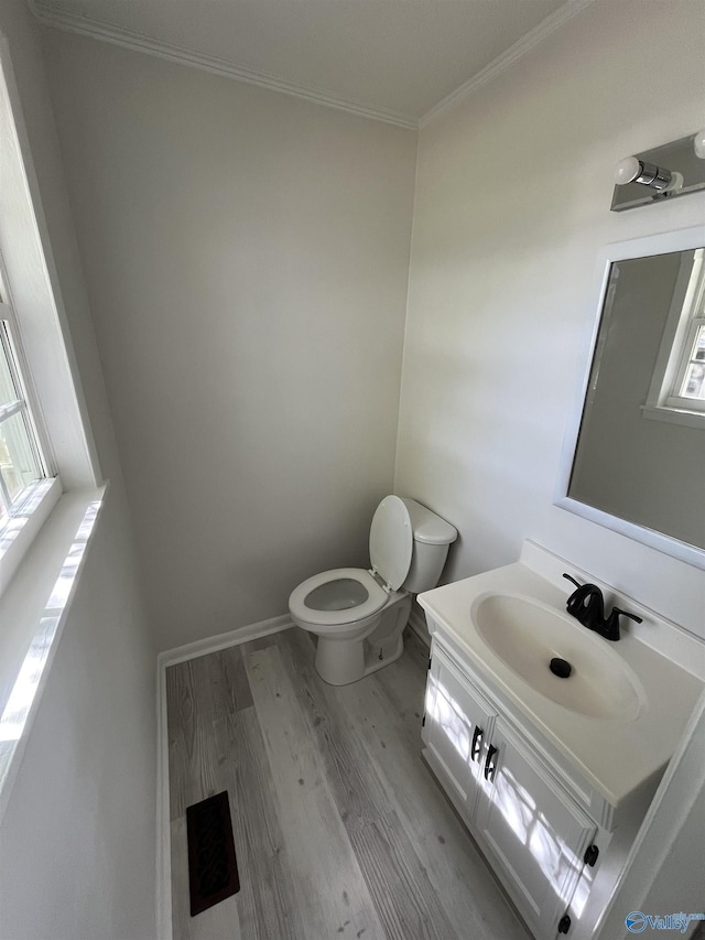 half bathroom with vanity, baseboards, ornamental molding, toilet, and wood finished floors