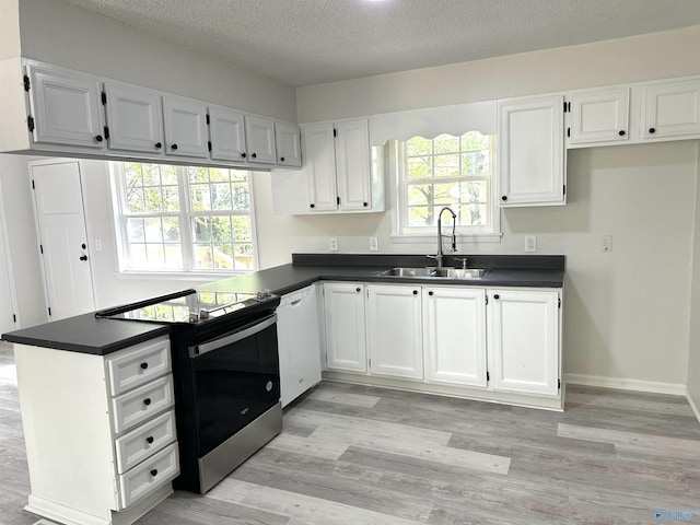 kitchen with electric stove, a sink, and dark countertops