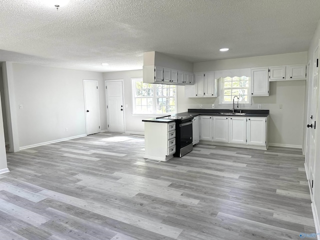kitchen featuring baseboards, a peninsula, electric range, dark countertops, and a sink