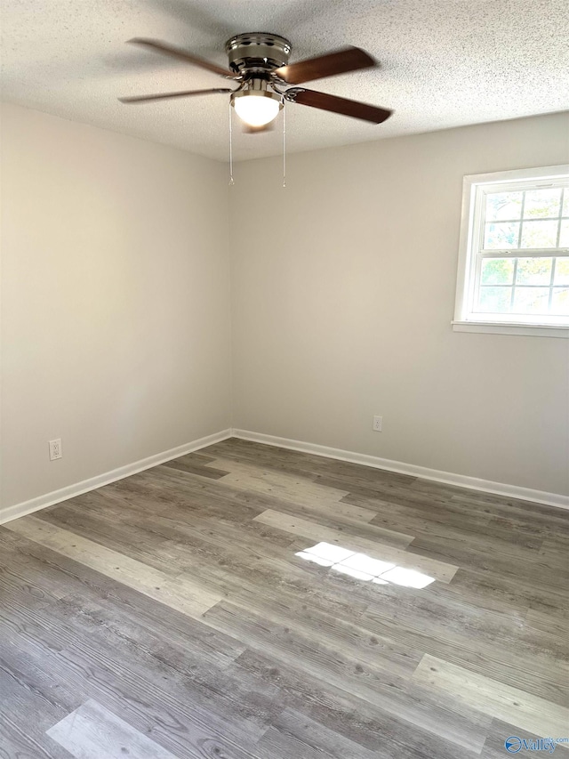 unfurnished room featuring a textured ceiling, wood finished floors, baseboards, and a ceiling fan