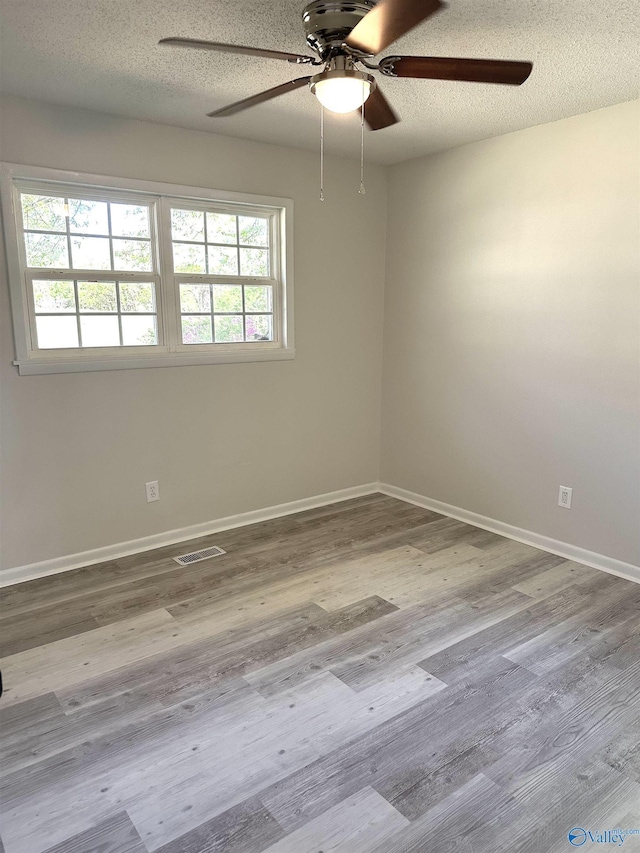 unfurnished room featuring visible vents, a textured ceiling, a ceiling fan, and a healthy amount of sunlight