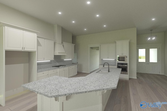 kitchen featuring a large island, sink, oven, white cabinets, and cooktop