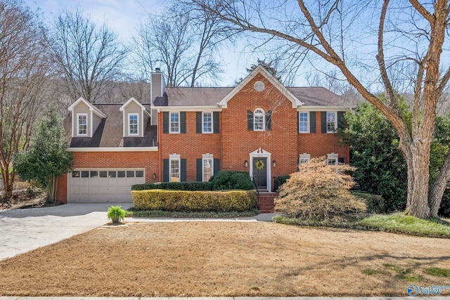 colonial inspired home featuring a garage, brick siding, concrete driveway, and a chimney