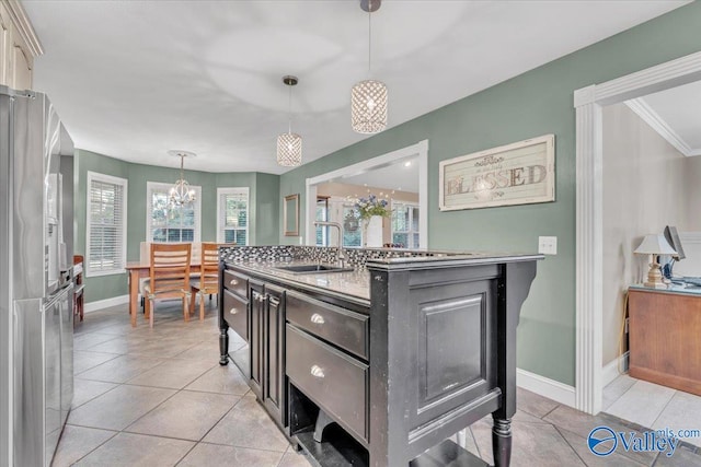 kitchen with pendant lighting, an island with sink, sink, and light tile patterned floors