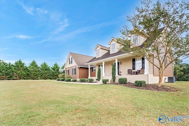 new england style home featuring cooling unit, covered porch, and a front yard