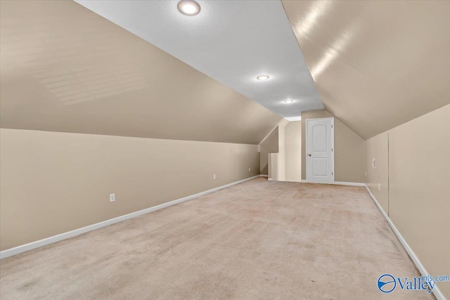 bonus room with light colored carpet and lofted ceiling