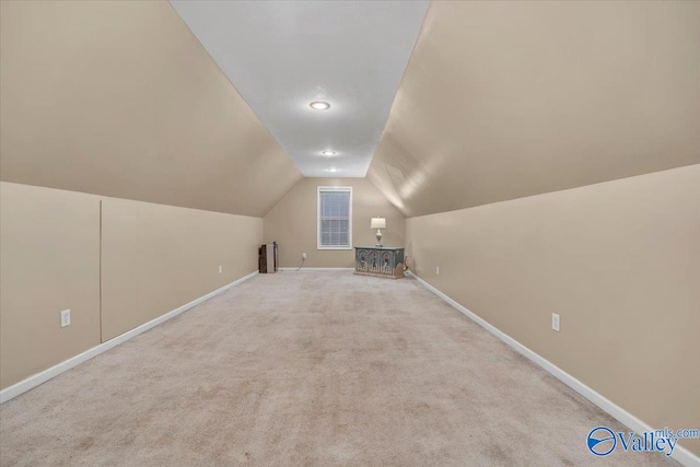 additional living space featuring light colored carpet and vaulted ceiling