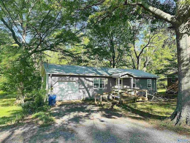ranch-style house featuring a wooden deck, driveway, and an attached garage