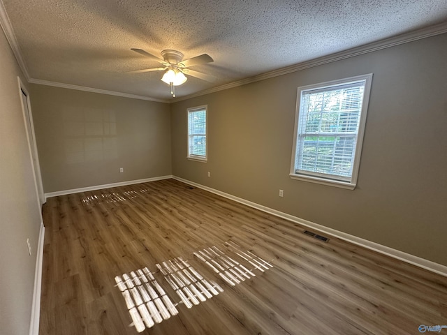 empty room with wood finished floors, ceiling fan, visible vents, a textured ceiling, and crown molding