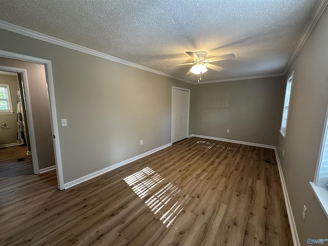 empty room with baseboards, wood finished floors, ceiling fan, and a textured ceiling