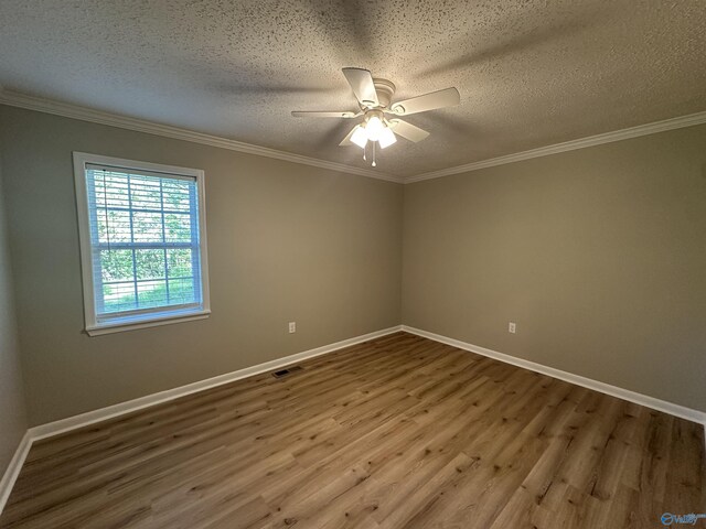 spare room featuring a ceiling fan, visible vents, wood finished floors, and a textured ceiling