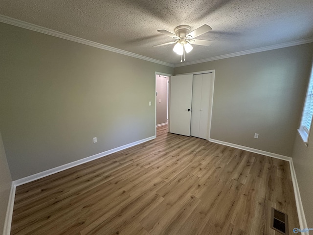 unfurnished bedroom featuring baseboards, visible vents, wood finished floors, and a textured ceiling