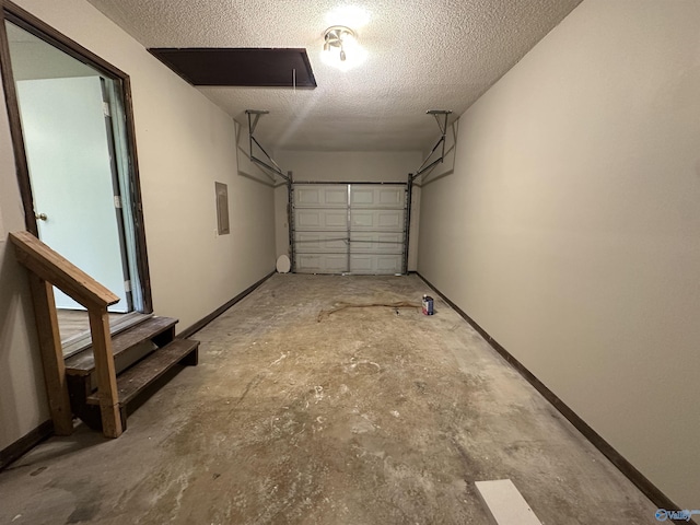 garage featuring electric panel and baseboards