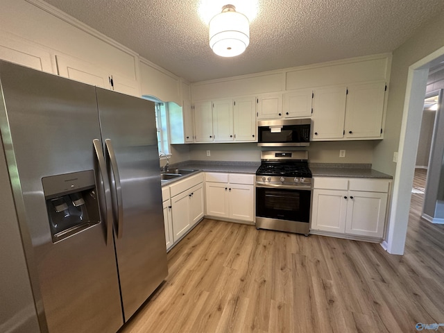 kitchen with appliances with stainless steel finishes, white cabinets, and a sink
