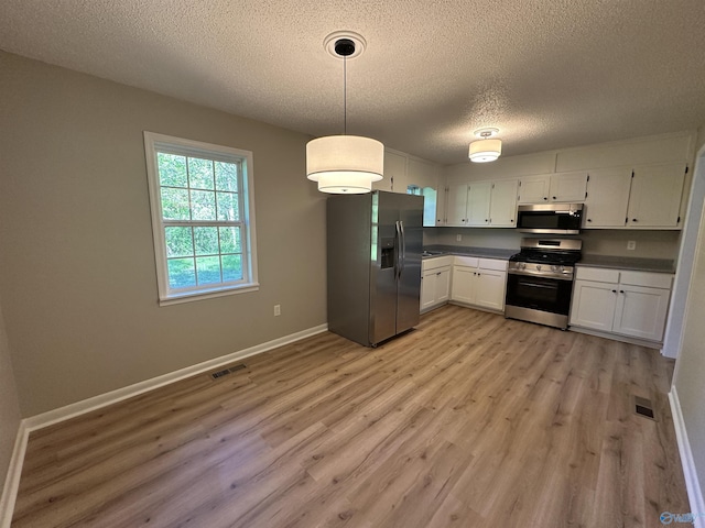 kitchen with a textured ceiling, visible vents, light wood-style flooring, and stainless steel appliances