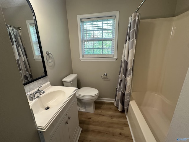 full bathroom featuring wood finished floors, shower / bath combo with shower curtain, toilet, vanity, and baseboards