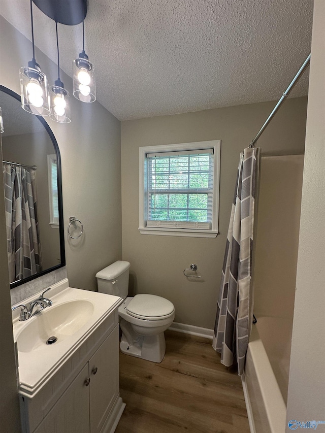 full bath with vanity, shower / bath combo with shower curtain, toilet, a textured ceiling, and wood finished floors
