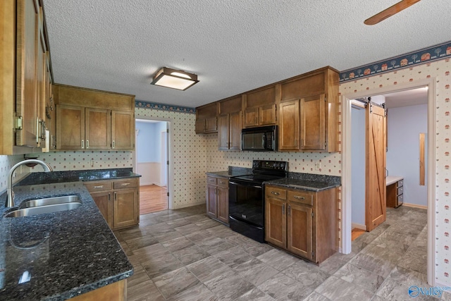 114 Butch Cir, Hazel Green, AL 35750 - kitchen featuring black appliances, wallpapered walls, dark stone countertops, a textured ceiling, and a barn door