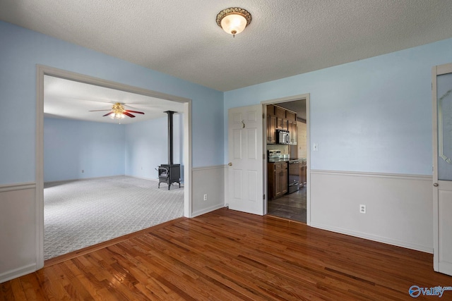 114 Butch Cir, Hazel Green, AL 35750 - empty room featuring a wood stove, dark wood-style floors, ceiling fan, and a textured ceiling