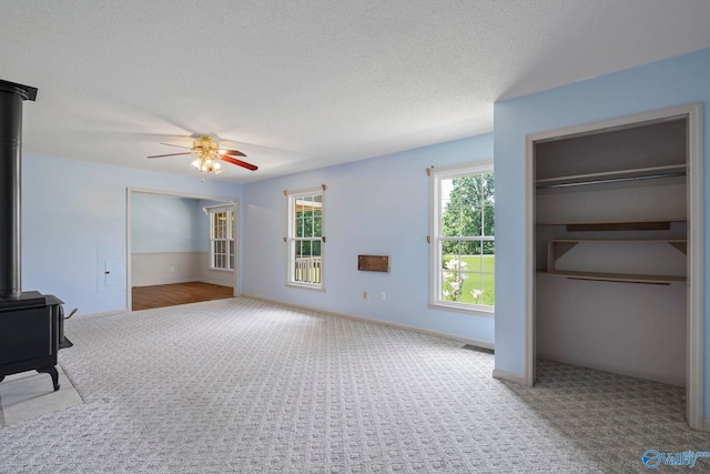 114 Butch Cir, Hazel Green, AL 35750 - unfurnished living room featuring a wood stove, carpet floors, a ceiling fan, and a textured ceiling