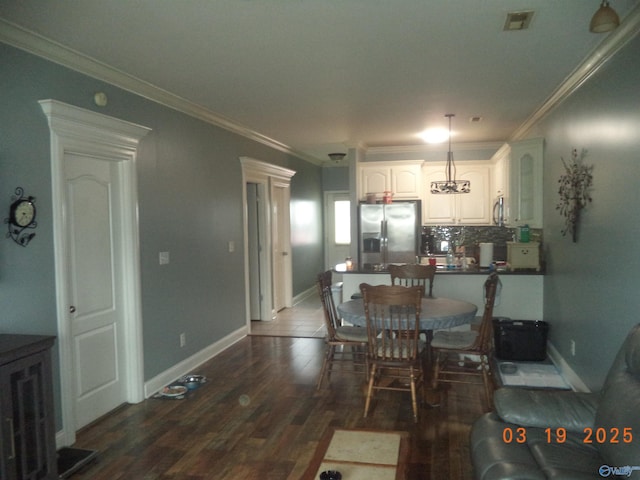 dining room featuring dark wood finished floors, visible vents, crown molding, and baseboards