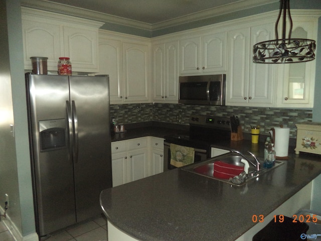 kitchen featuring a peninsula, a sink, stainless steel appliances, dark countertops, and tasteful backsplash
