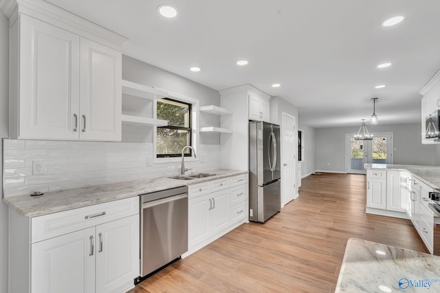 kitchen with pendant lighting, white cabinets, sink, decorative backsplash, and stainless steel appliances