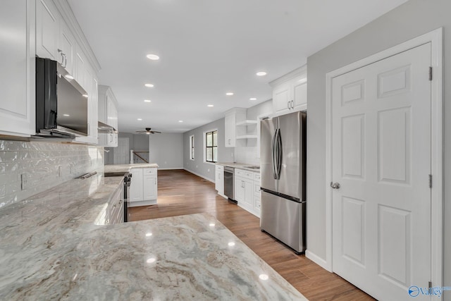 kitchen featuring kitchen peninsula, white cabinetry, stainless steel appliances, and light stone counters