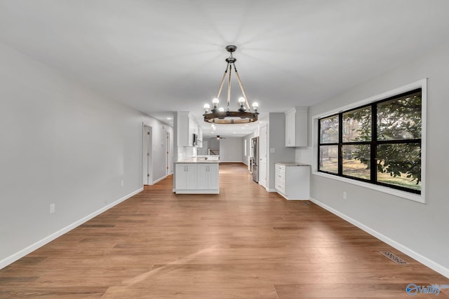 unfurnished living room with a chandelier and light wood-type flooring