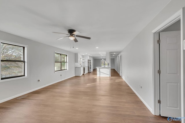 unfurnished living room with light hardwood / wood-style flooring and ceiling fan