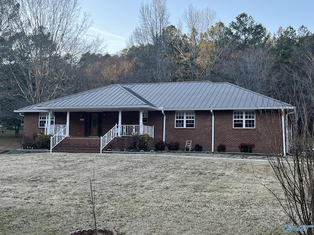 single story home with covered porch, metal roof, brick siding, and a standing seam roof