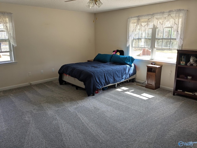 carpeted bedroom featuring a textured ceiling, multiple windows, and baseboards