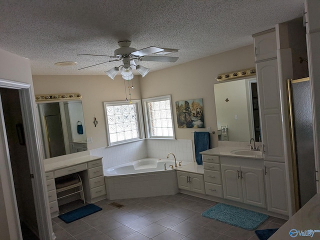 full bathroom with a textured ceiling, a garden tub, vanity, and tile patterned floors